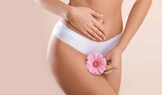Young woman with flower on light background. Gynecology concept